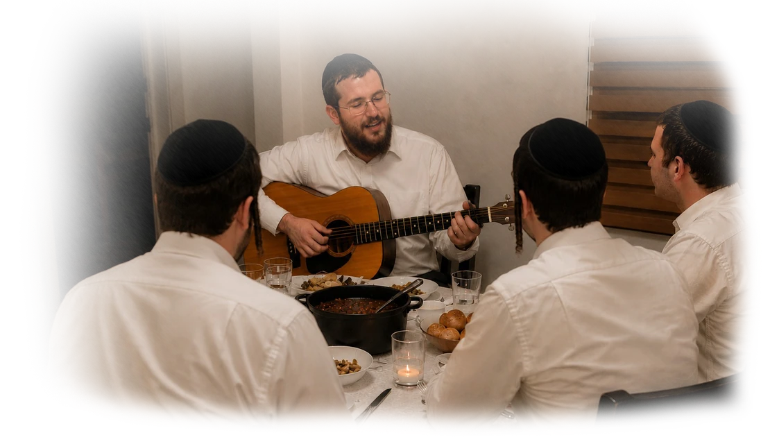 Nachman playing guitar at a table with students
